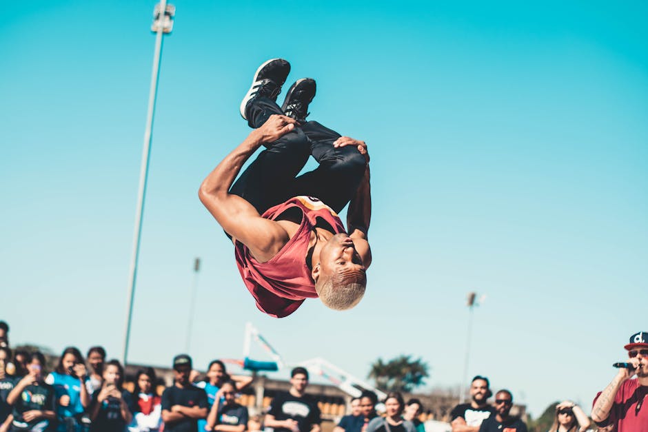 A man skillfully performs a backflip at an outdoor event on a sunny day.