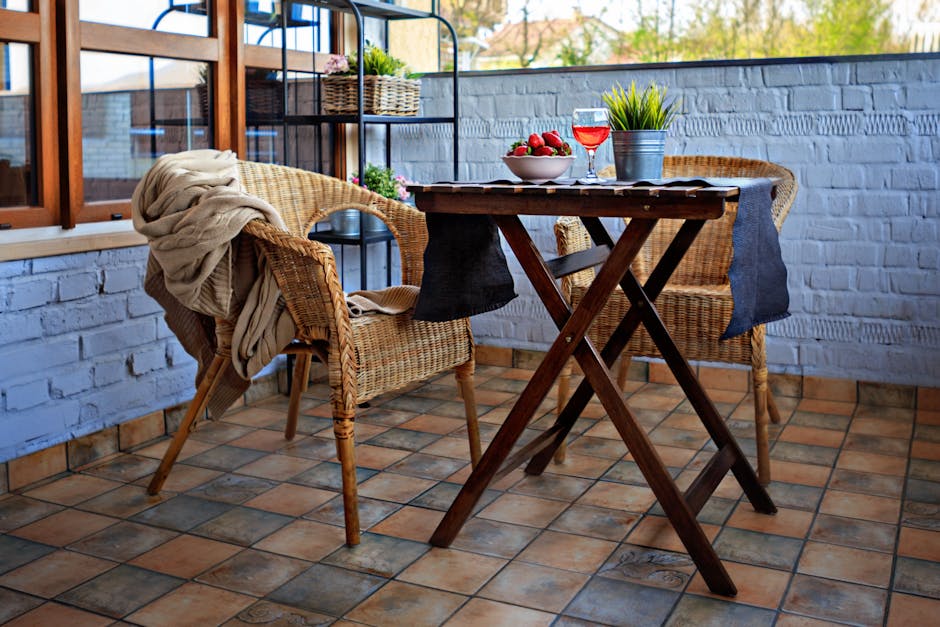 A charming outdoor patio scene featuring a warm, inviting dining setup with wicker chairs and a table set with strawberries and wine.