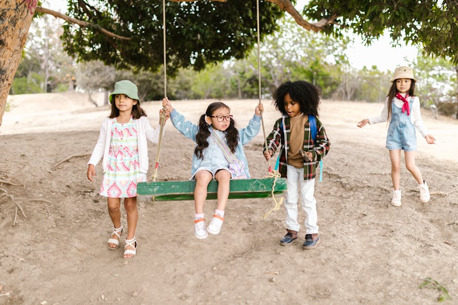 A group of diverse children playing on a tree swing outdoors, enjoying a sunny day.
