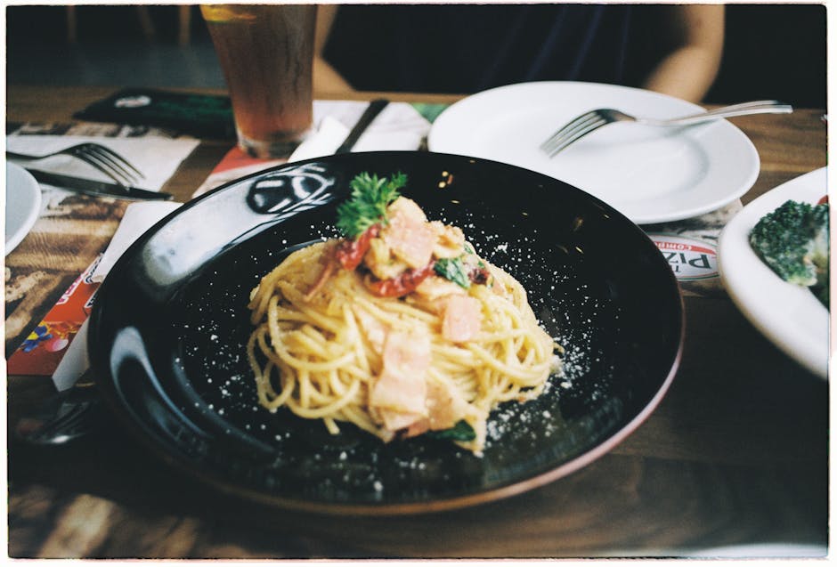 Close-up of a savory Italian pasta garnished with herbs on a black plate.