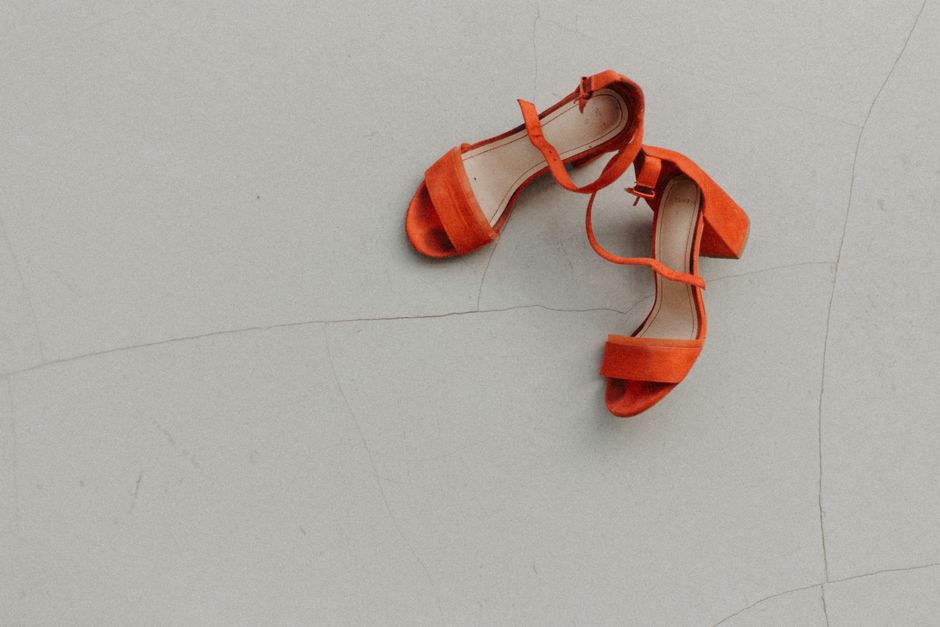Stylish red high heels placed on a neutral surface, perfect for fashion and lifestyle content.