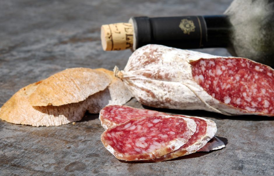 Close-up of sliced salami, rustic bread, and wine for a perfect snack.