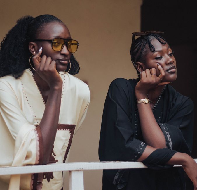 Two stylish African women enjoying a relaxed moment outdoors, exuding elegance and confidence.